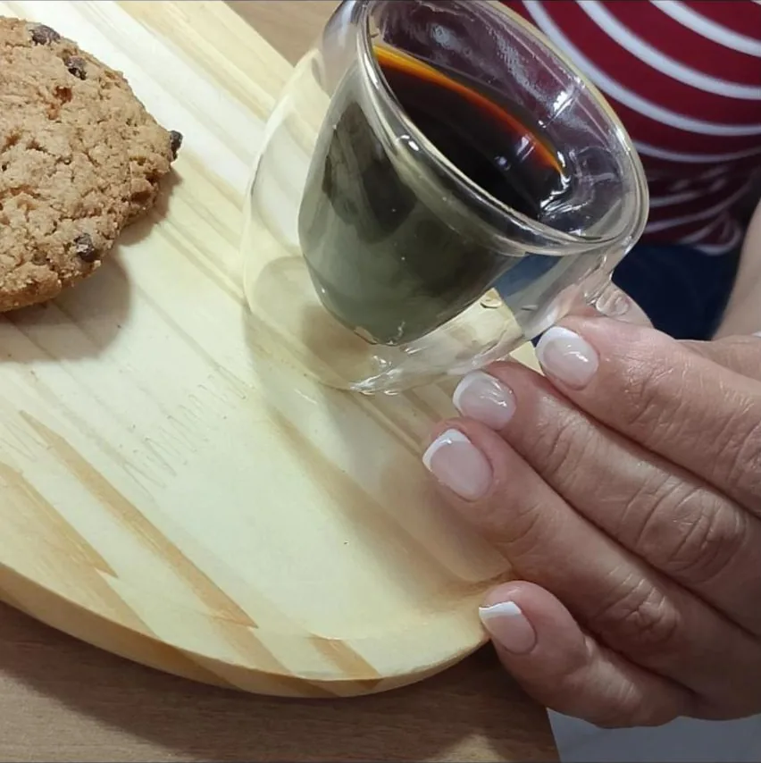 Mão com francesinha clássica segurando um copo de café